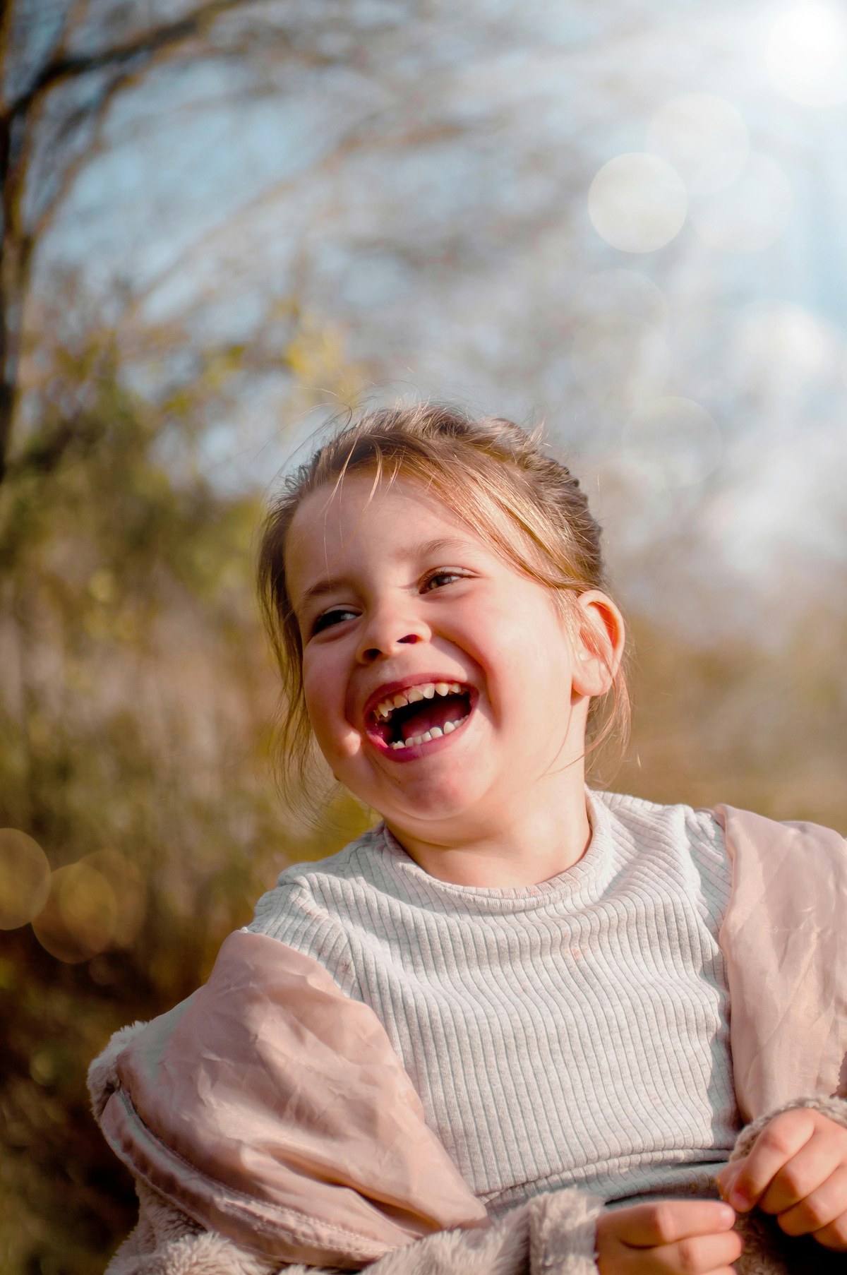 A young girl laughing in afternoon sunlight, present and joyful. The kind of moment parents want back.