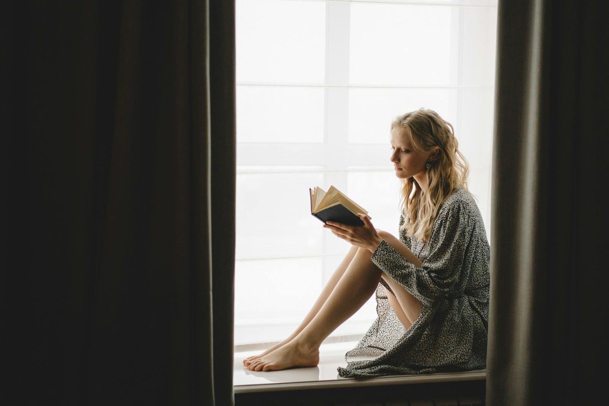 A woman reading by a window in soft morning light, settled and present