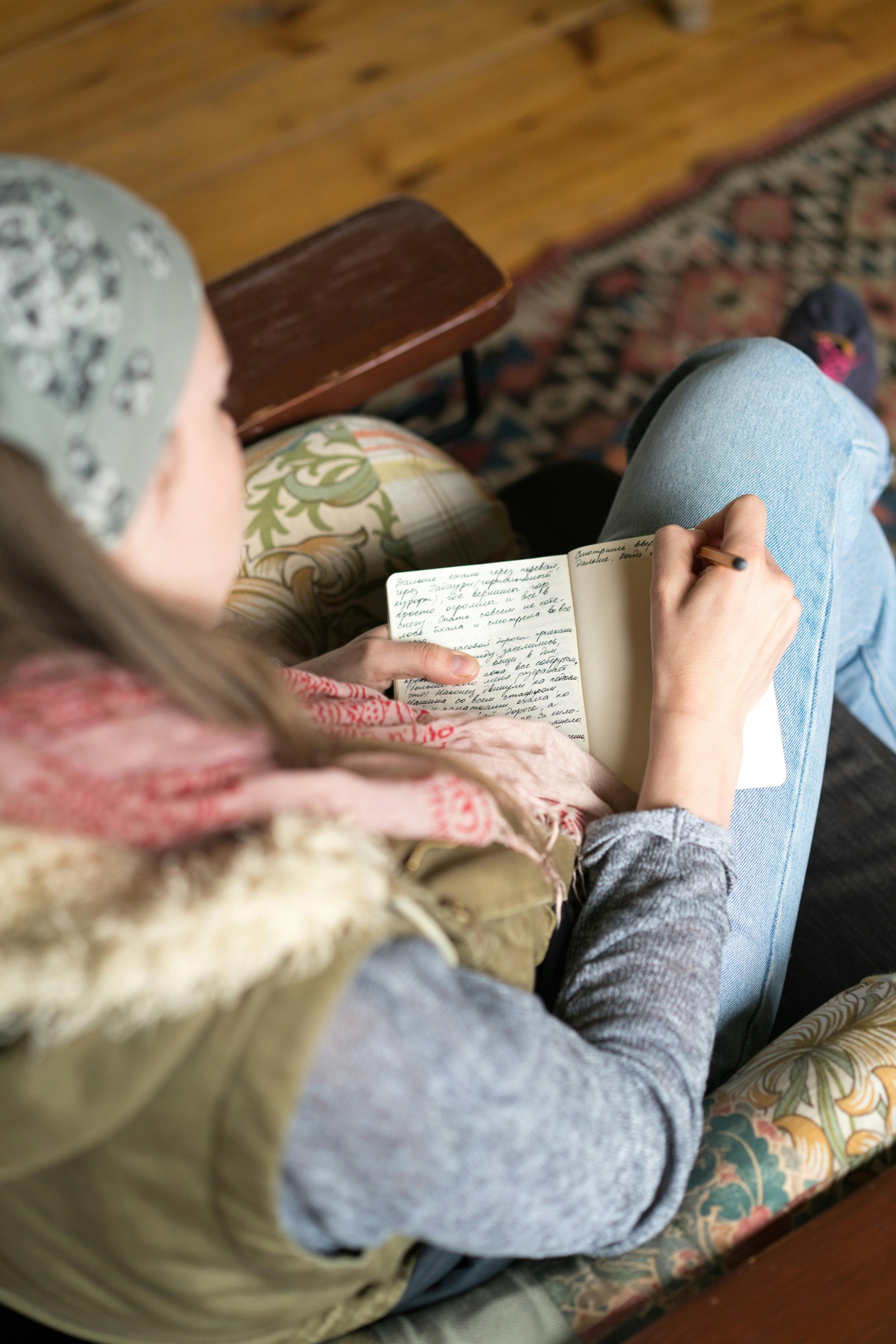 Hands writing in a journal on a wooden table in soft natural light