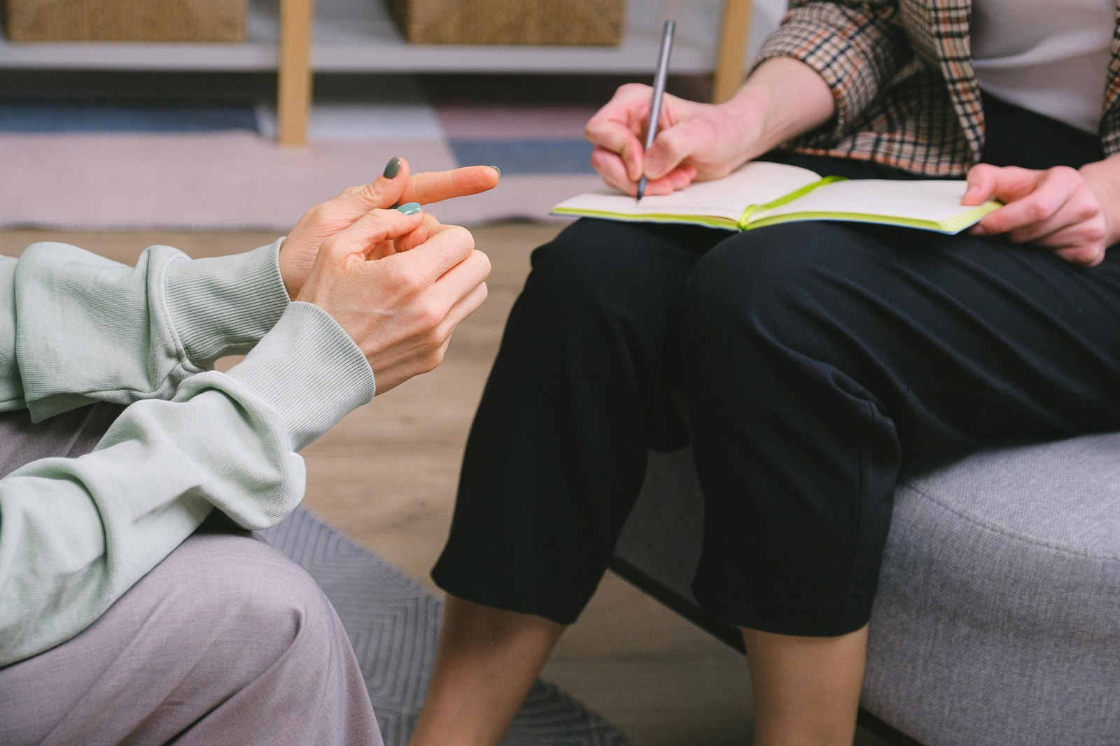 Two people in conversation on a couch, hands and posture in focus, faces out of frame