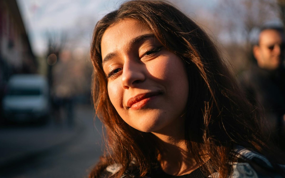 Young woman smiling warmly in soft sunlight, visibly relaxed
